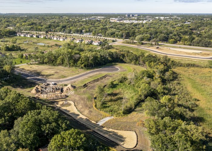 Aerial view of road construction amid wooded suburban landscape
