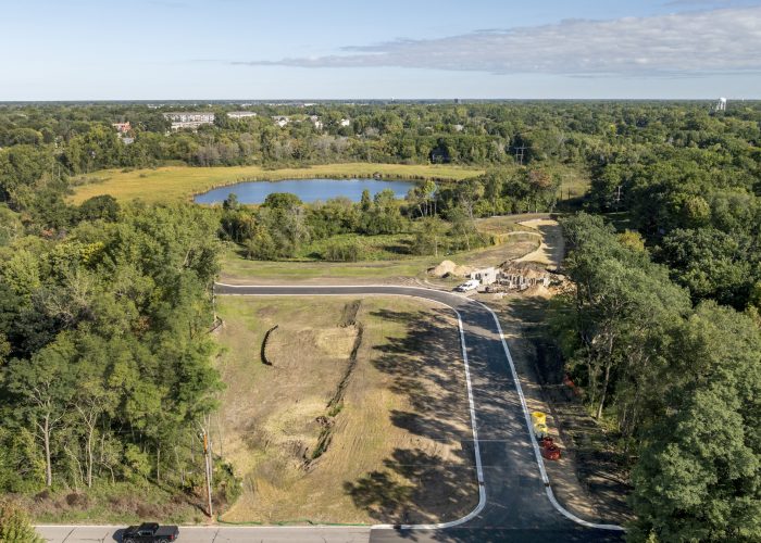 Aerial view of new road construction near wooded pond