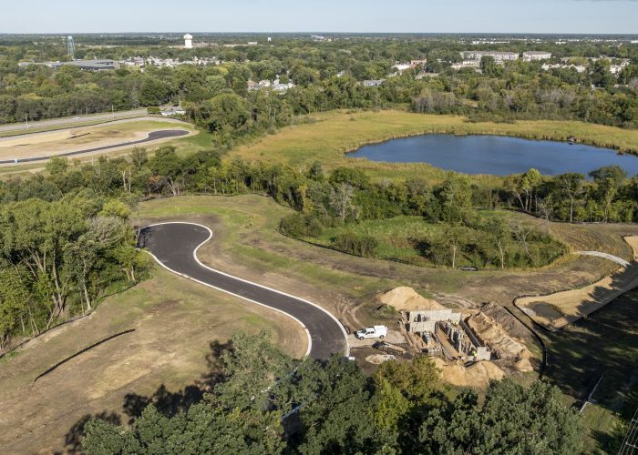 Aerial view of road construction near wooded pond