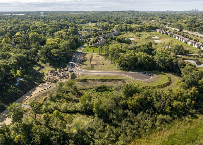 Aerial view of suburban road construction amid wooded neighborhoods